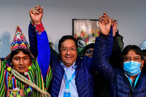 Bolivia's leftist presidential candidate Luis Arce (C), of the Movement for Socialism party, celebrates with running mate David Choquehuanca (R) early on October 19, 2020, in La Paz, Bolivia. - Bolivian presidential candidate Luis Arce, the leftist heir to former leader Evo Morales, appeared headed to a first-round election victory on October 18, 2020 with 52.4 percent of the vote, according to an authoritative exit poll from TV station Unitel. (Photo by RONALDO SCHEMIDT / AFP)