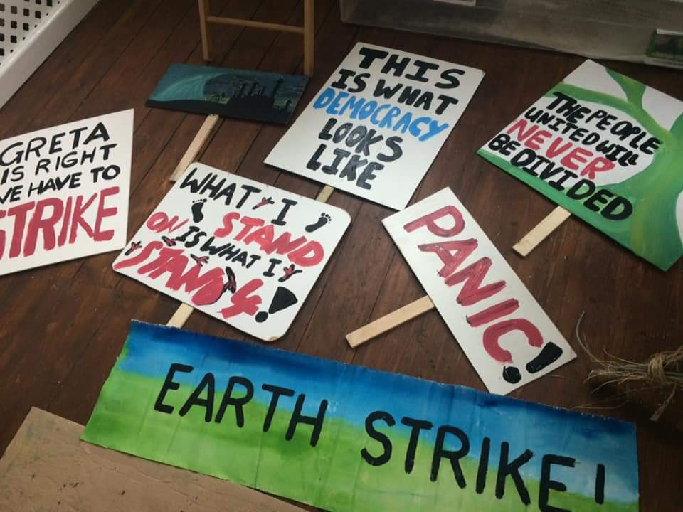 Lots of painted protest banners laid out on a wooden floor.