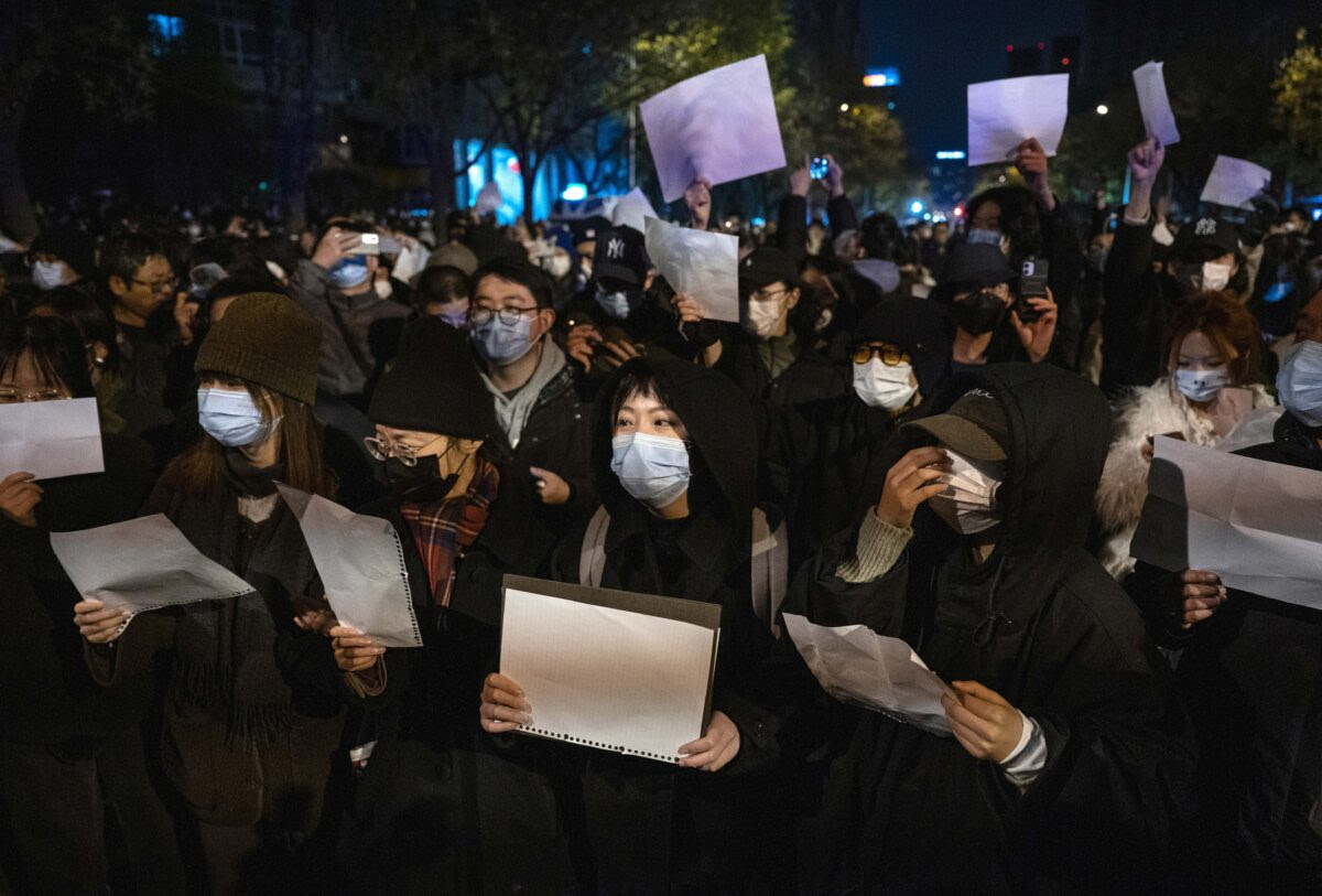 Những người biểu tình giơ cao các mảnh giấy trắng để phản đối sự kiểm duyệt và các biện pháp zero COVID nghiêm ngặt của Trung Quốc, tại Bắc Kinh hôm 27/12/2022. (Ảnh: Kevin Frayer/Getty Images)