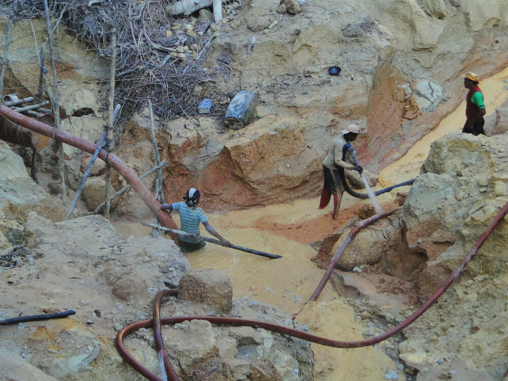 Três garimpeiros extraem ouro ilegal no rio Tapajós. Na imagem é possível ver a terra escavada e dragas drenando o minério