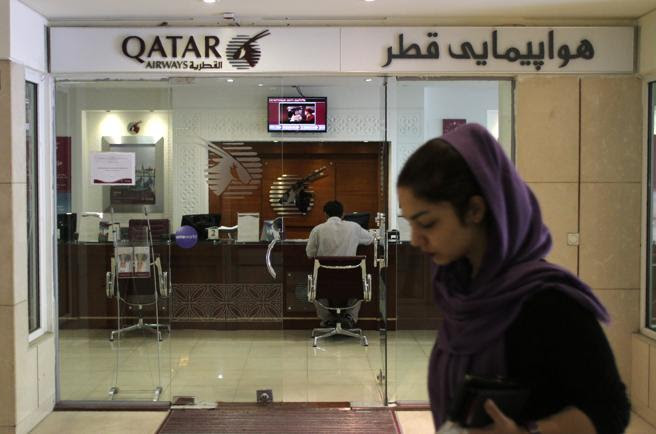 Una mujer iraní camina frente a una oficina de Qatar Airways en Teheran