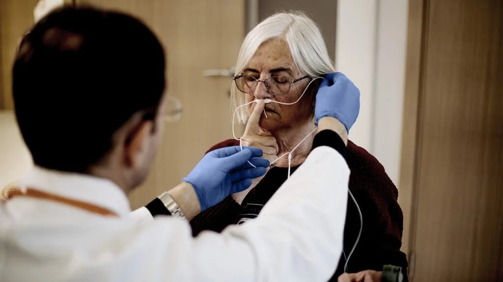 male doctor teaching older woman how to use oxygen support