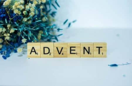The word "Advent" spelled in scrabble letters with greens in background.