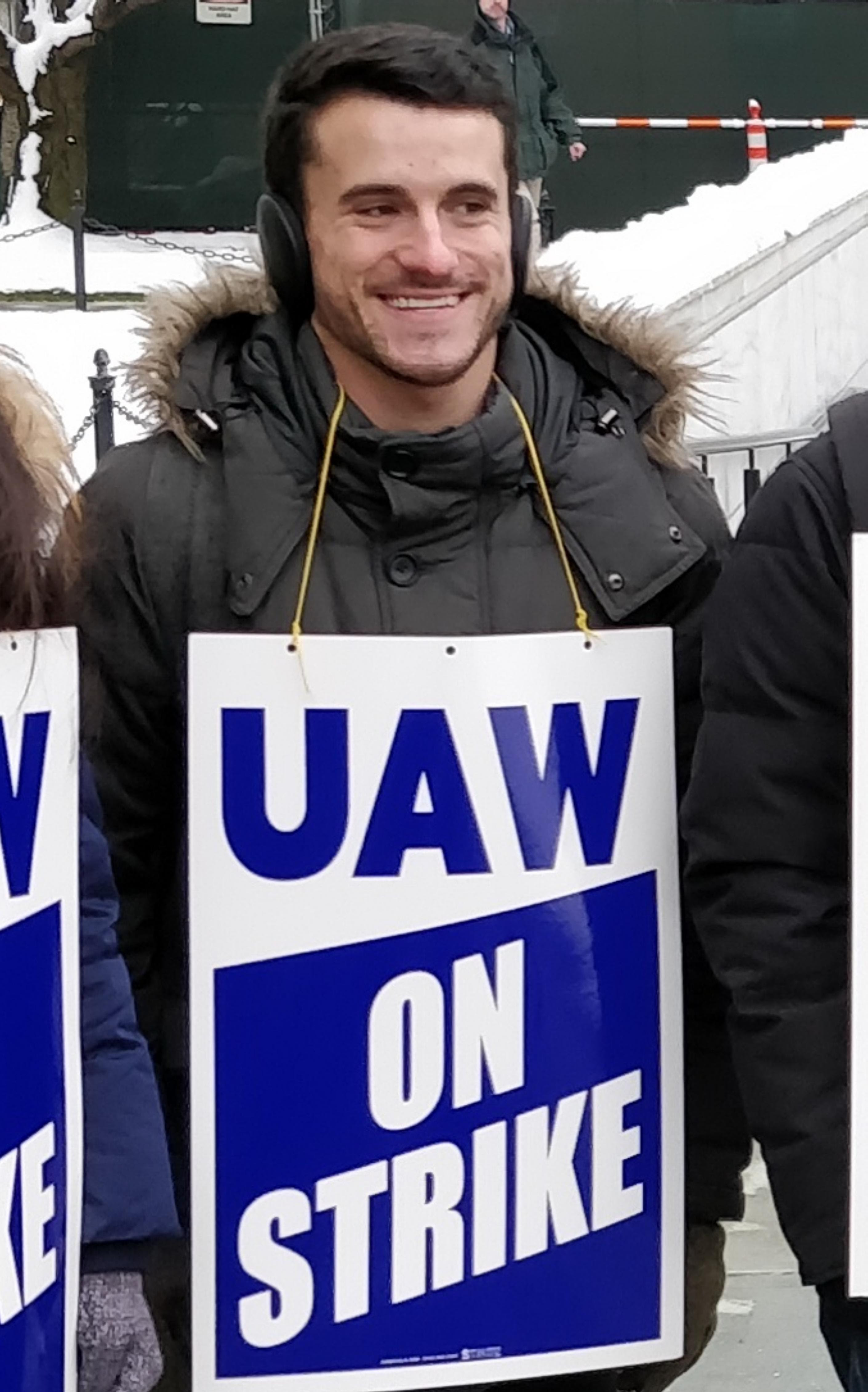 Photo of CEEC co-chair Eric Cohn wearing a UAW On Strike placard