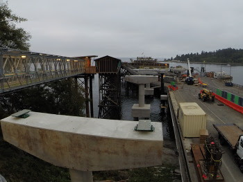 View of Bainbridge terminal with existing overhead walkway on the left, vehicle lanes on the right and concrete pillars in the water in the center