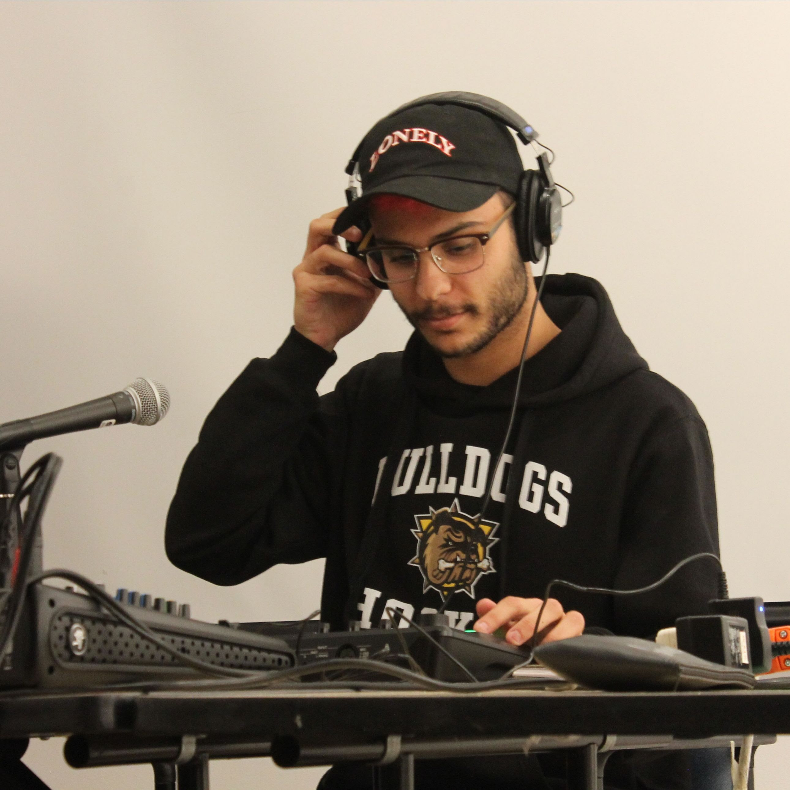a photo of a man wearing headphones near microphone and musical instrument 