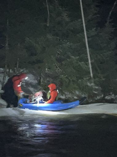 Ranger and rescued hiker in a small blue boat on the water during rescue