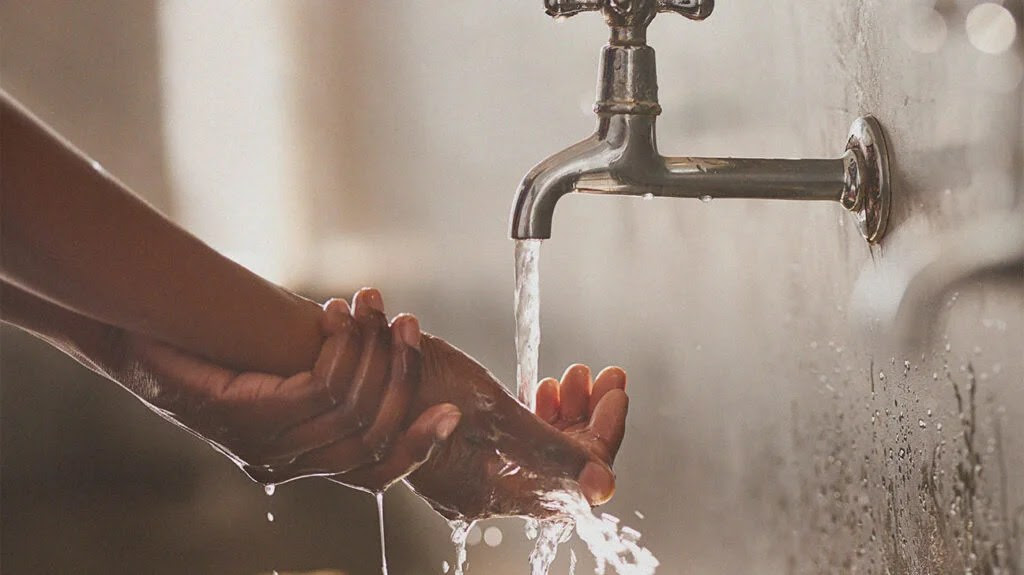 a person with a burned finger runs the burned finger under cool water from a faucet