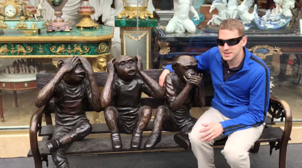 Jason Corning sitting on bench sitting next to sculpture (see no evil, hear no evil, speak no evil)