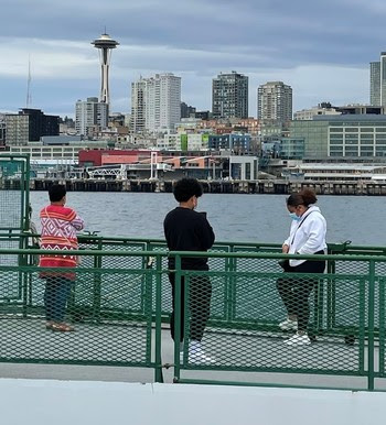 Photo of people wearing masks while on outdoor deck of a ferry