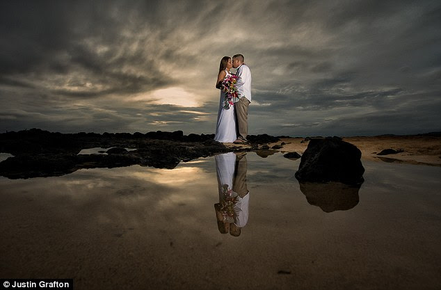 Island setting: A couple stand out in white against a dark and wet background in Kauai, Hawaii
