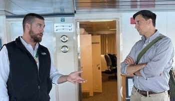 Two people speaking with each other in the pilothouse of a ferry
