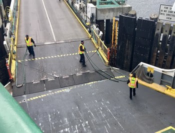 Three ferry workers handling the ropes that tie up a ferry at dock