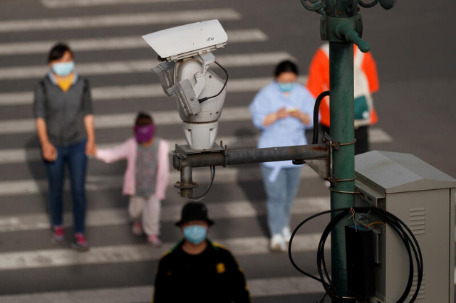 A CCTV security surveillance camera overlooks a street as people walk following the spread of the coronavirus disease (COVID-19) in Beijing, China May 11, 2020. REUTERS/Thomas Peter