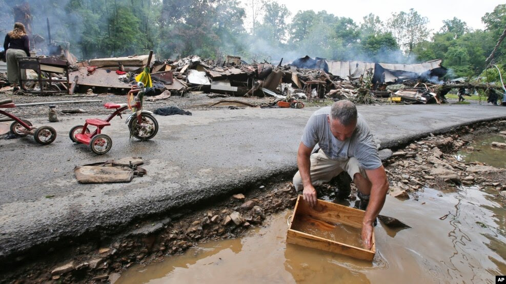 Ông Mark Lester rửa một chiếc hộp khi ông dọn dẹp sau trận lũ lụt nghiêm trọng ở White Sulphur Springs, West Virginia, ngày 24 tháng 6 năm 2016. 