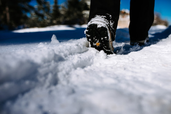 person wearing  hiking boots walking in snow