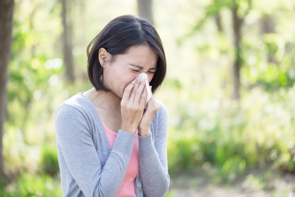 woman in the outdoors holding a tissue to her nose