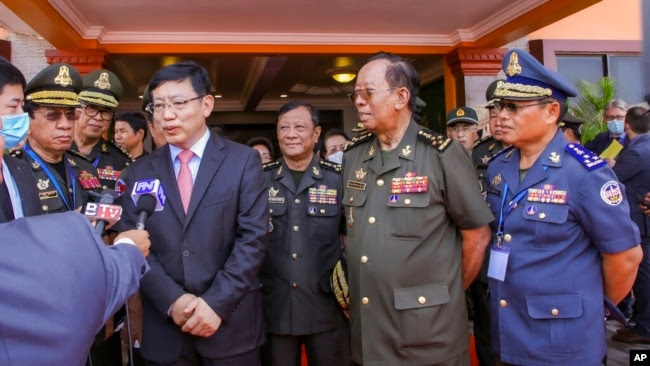 FILE - In this photo provided by Cambodia's Fresh News, Chinese Ambassador to Cambodia Wang Wentian talks to a reporter as Cambodian Defense Minister Tea Banh, second from right, listens during the groundbreaking ceremony for a shipyard repairing and rest