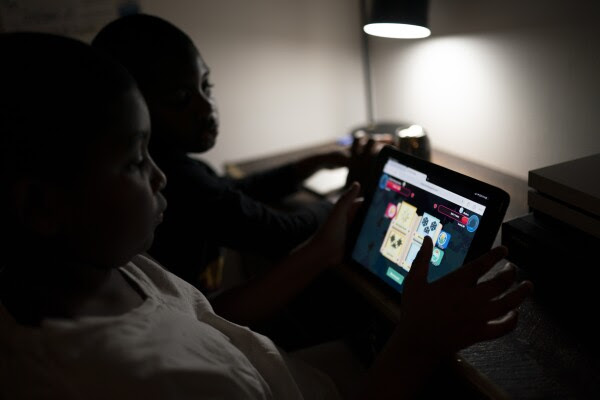 Isaiah Schneider, 9, left, and his brother Adam, 7, complete a level on their learning game played on a tablet computer, in their bedroom, Wednesday, Dec. 8, 2021, in the Brooklyn borough of New York. Their mother April Schneider says she is lucky her two oldest children attend the same school and can share technology. "When one computer is down, we can us the other," said Schneider. "There needs to be more computers. More staff. More outreach."