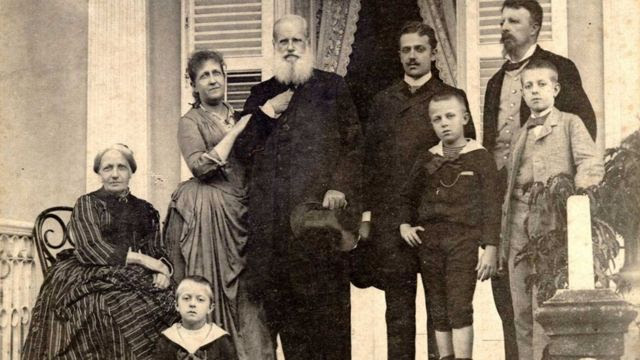 Família imperial posa em escadaria, em frente a casa