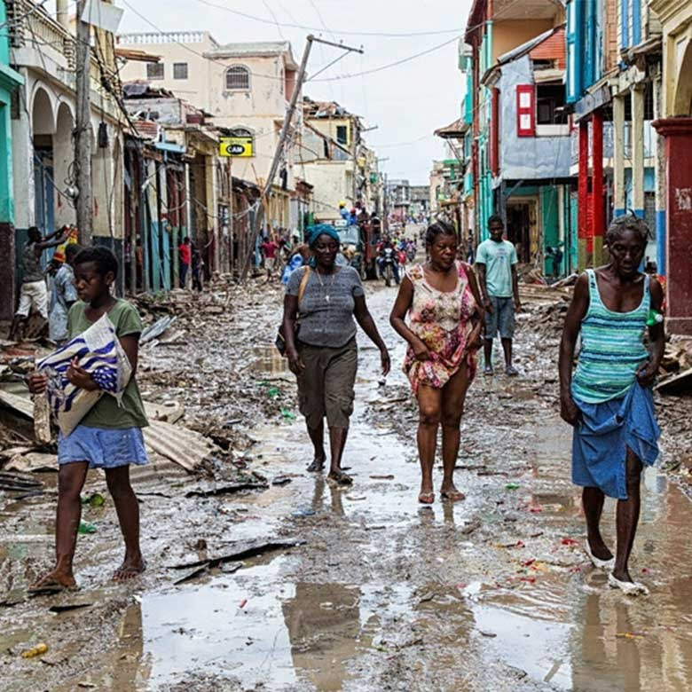 Cuatro mujeres caminan entre los escombros tras el paso de una tormenta