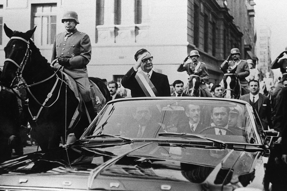 El presidente de Chile, Salvador Allende, saluda a sus seguidores desde su coche descubierto, en Santiago, pocas semanas después de su elección. A su lado, a caballo, es escoltado por el general Augusto Pinochet. AFP