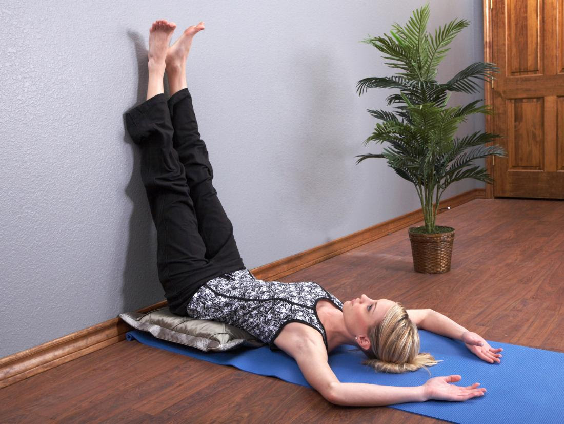 a woman lying on the floor and doing legs up the wall yoga pose.