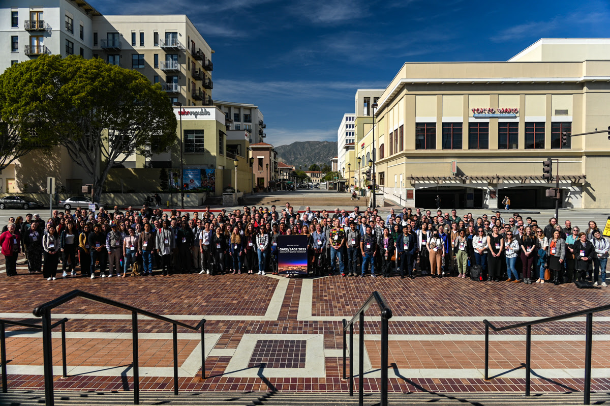 group photo of attendees outside convention center, buildings and mountains in the background