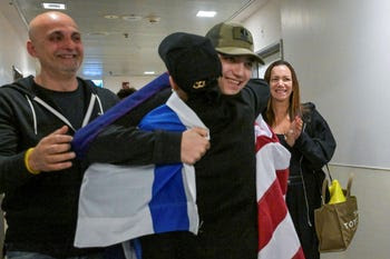 Idan Alexander, wrapped in Israeli and U.S. flags, reunites with his family at Ichilov Hospital in Tel Aviv. He fought Hamas terrorists on October 7 and survived 584 days in Gaza's tunnels.
