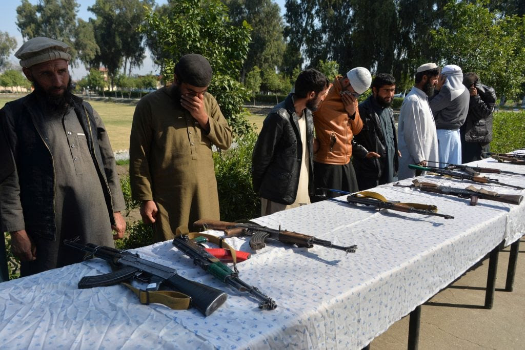 Former Afghan Taliban fighters stand next to weapons before handing them over as part of a government peace and reconciliation process at a ceremony in Jalalabad on March 1.