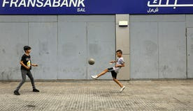 Boys play with a ball past a closed, fortified bank branch during a banks' strike, in Beirut, Lebanon last month.