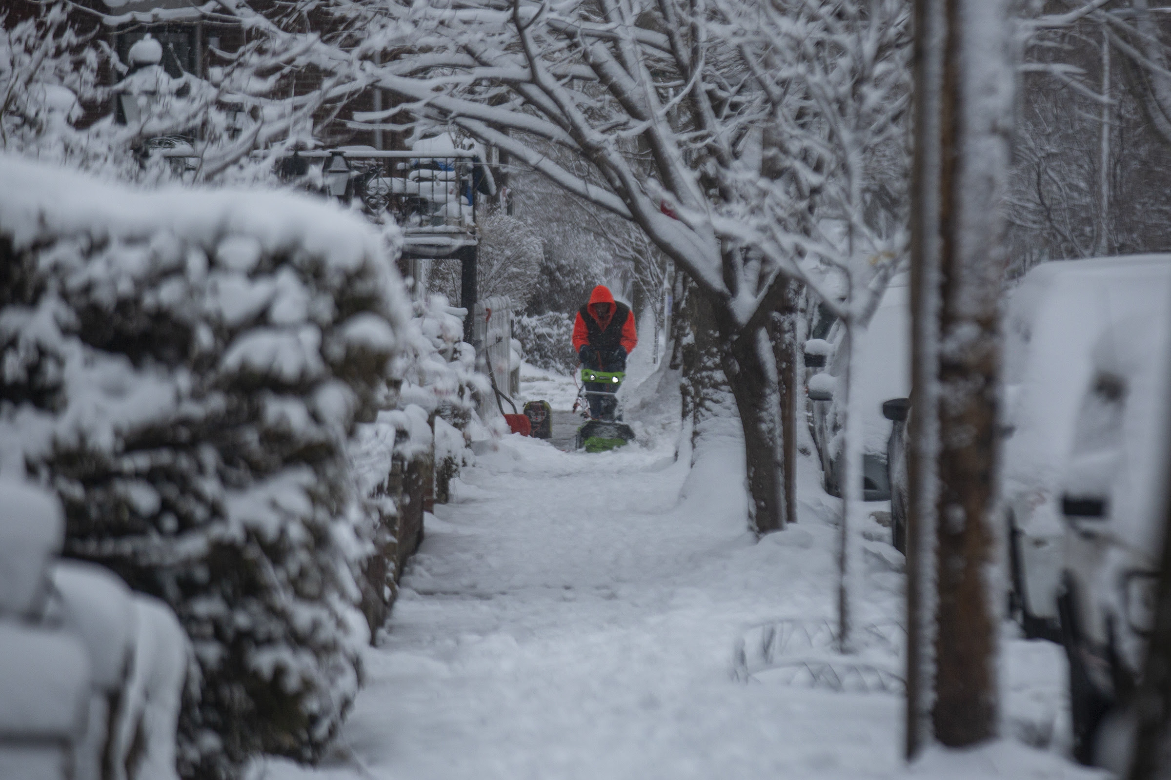 A man using a snow blower to clear out the sidewalk along Larchwood Avenue in West Philadelphia on Tuesday.