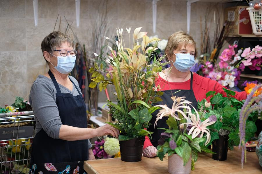 Two women arrange flowers in an MCC Thrift shop