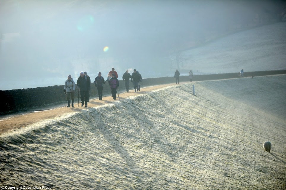 Hearty hiking: Ramblers cutting through the early morning sun rising over the morning frost at Dove Stone Reservoir in Oldham, Greater Manchester where temperatures plunged overnight