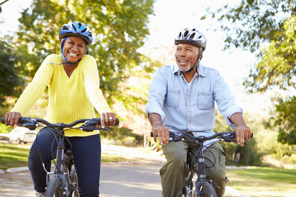 African american man and woman riding bicycles and helmuts