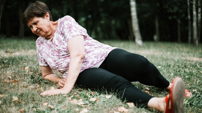 Senior woman who has fallen outside on the lawn.