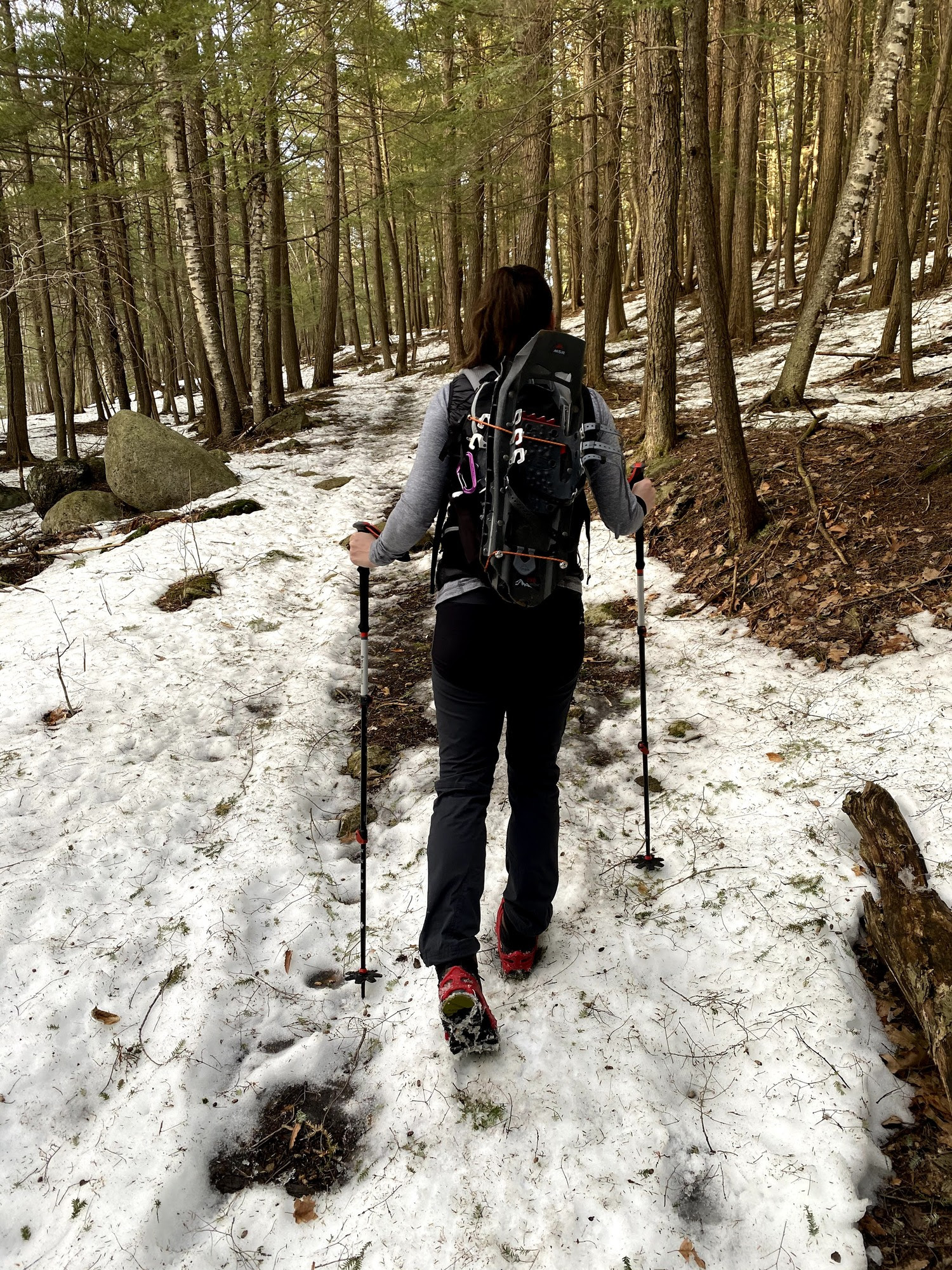 person hiking on a snow covered trail with hiking poles