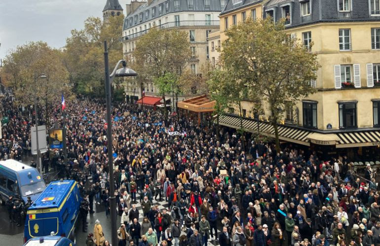 A large crowd of people marching along a street on Paris
