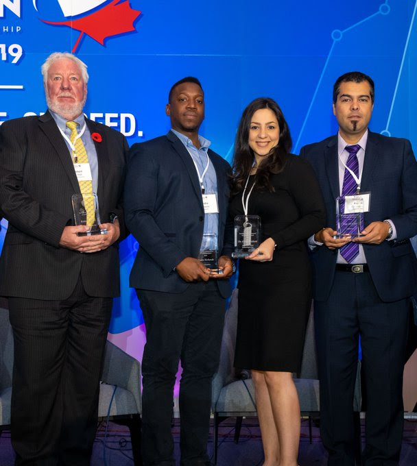 Group shot of the winners of the 2019 Immigrant Entrepreneur Awards holding their trophies.