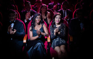 Beautiful young women clapping with crowd in opera