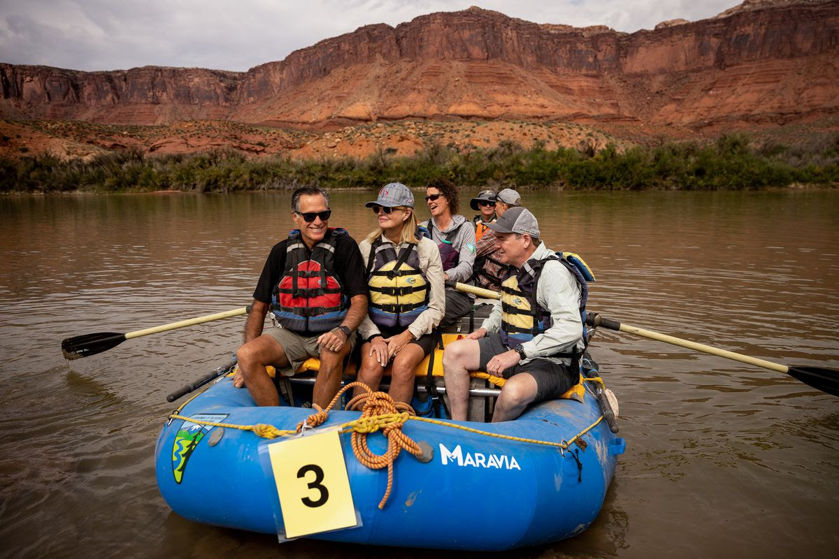 Sen. Mitt Romney, his wife, Ann, and Sen. Michael Bennet, D-Colo., sit together in a raft while they float a section of the Colorado River northeast of Moab.