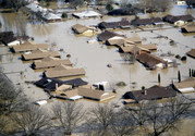 Several houses that are flooded up to the roofline in a neighborhood. 