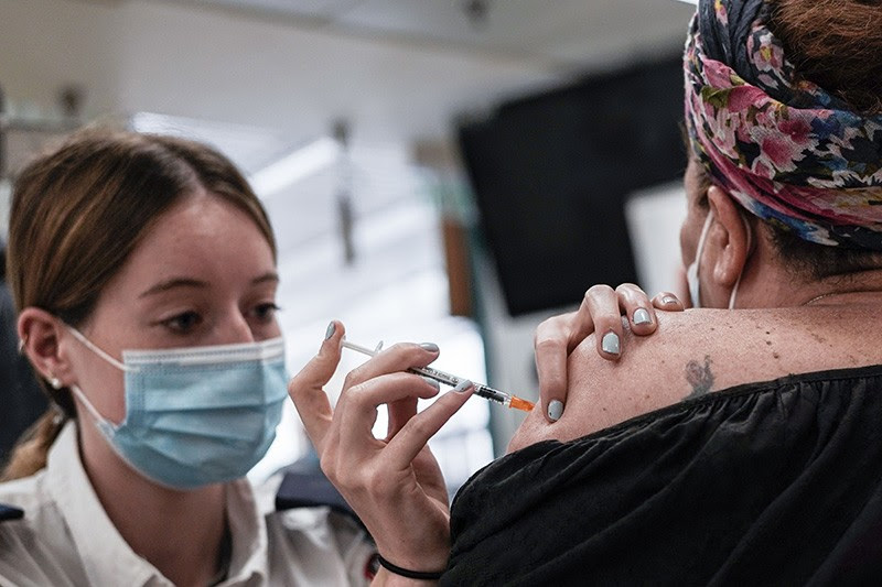 A paramedic injects a vaccine into a person's shoulder.