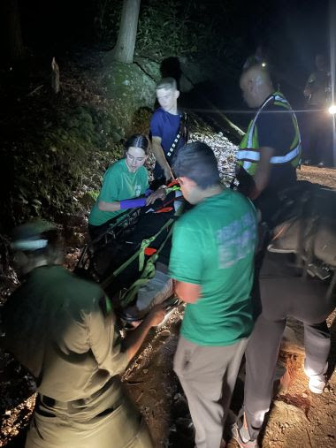 Rangers and EMS tend to injured hiker on a trail at night