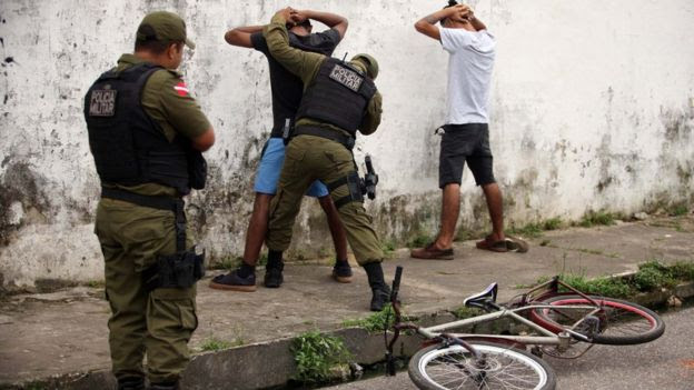 Policiais militares revistam homens nas ruas de Belém, Pará