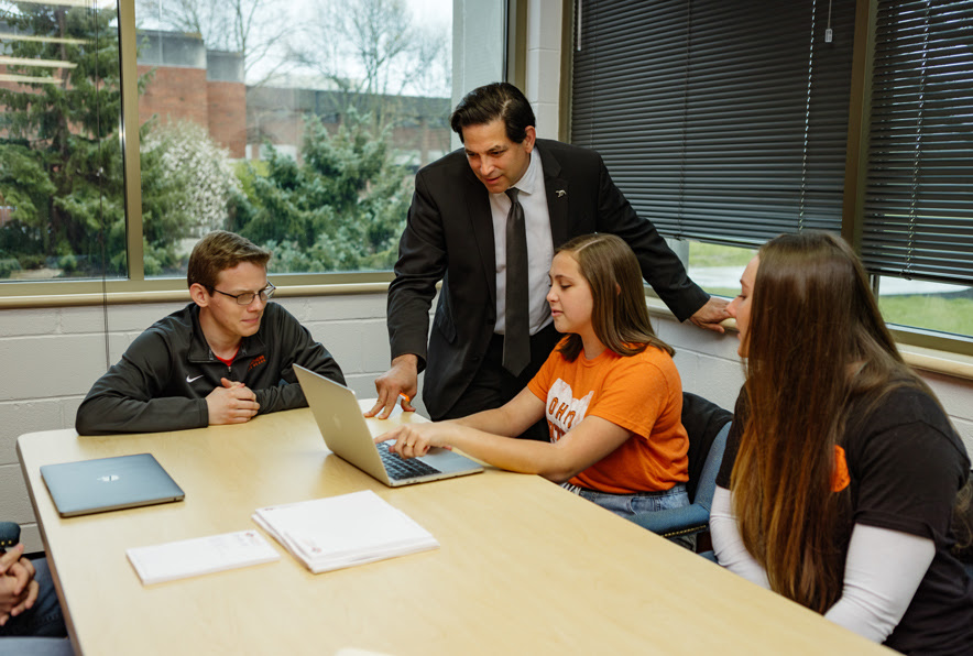 Photo of students with a faculty looking at laptop