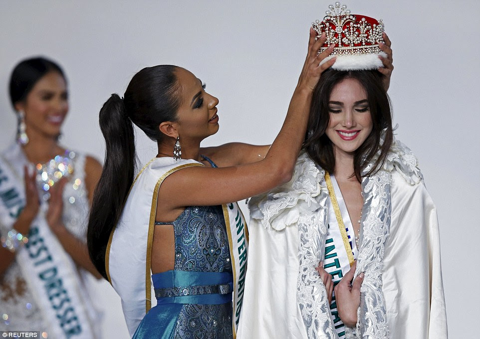 The pearl-dotted, red velvet and fur trim crown and an embroidered white cloak were placed on Edymar by a smiling Miss International 2014, Valerie Hernandez Matias from Puerto Rico 