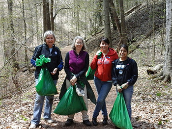 volunteers in forest holding trash bags