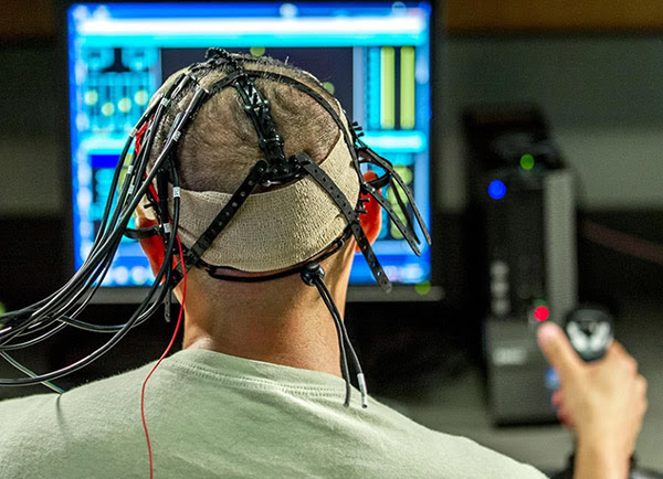 The back of the head view of a test participant with electrodes and wires attached to his shaved head