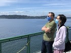 Photo of people wearing a mask while on outdoor deck of ferry